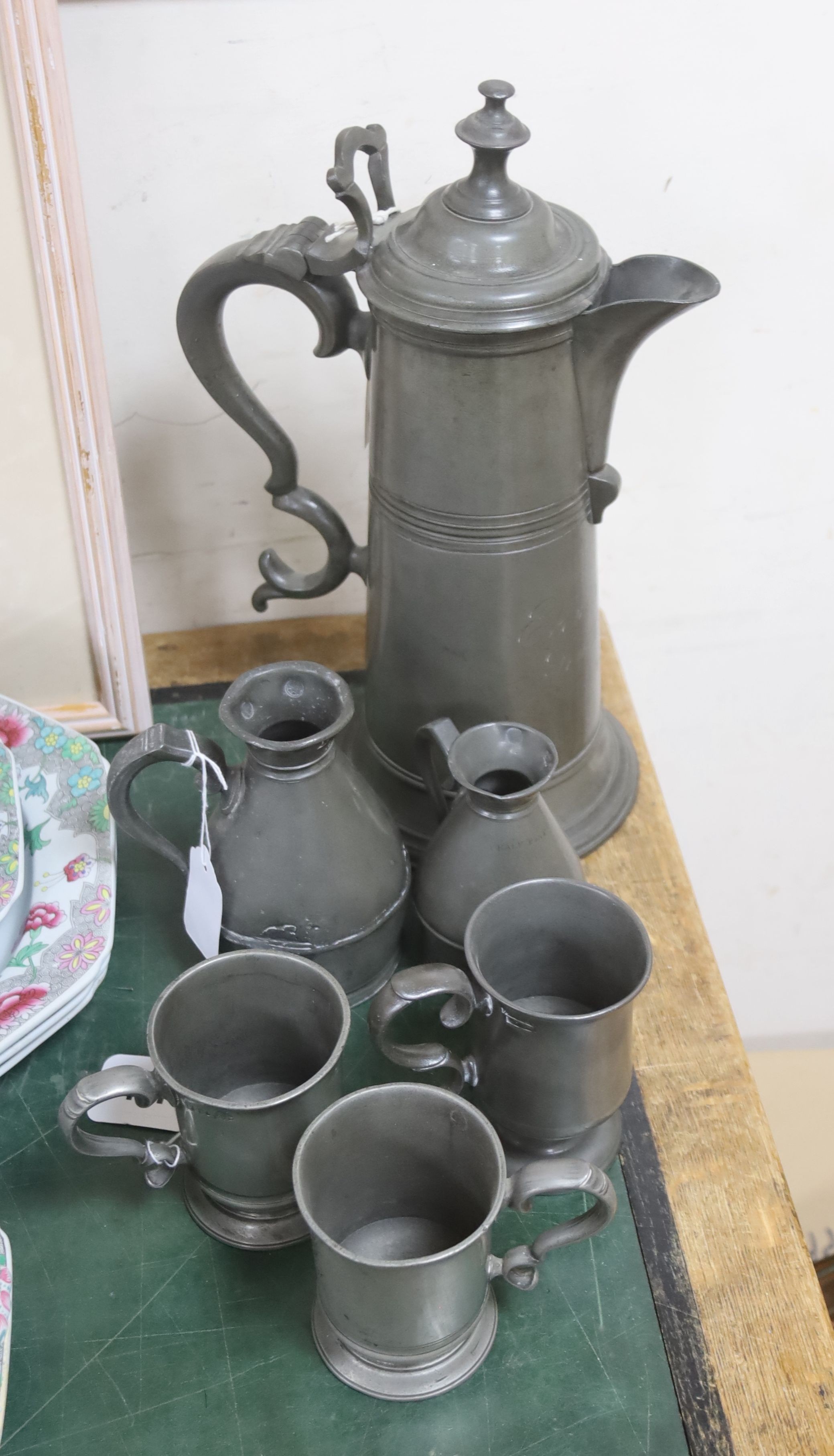 A mid-19th century pewter jug, of tapered form with double scroll handle (inscribed), three 19th century pewter mugs and two measures (6)